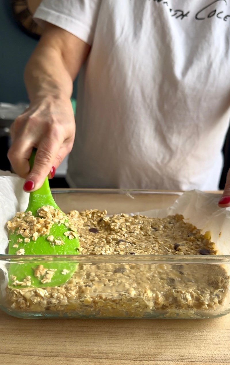 pressing down banana oat bars into an 8x8 pan
