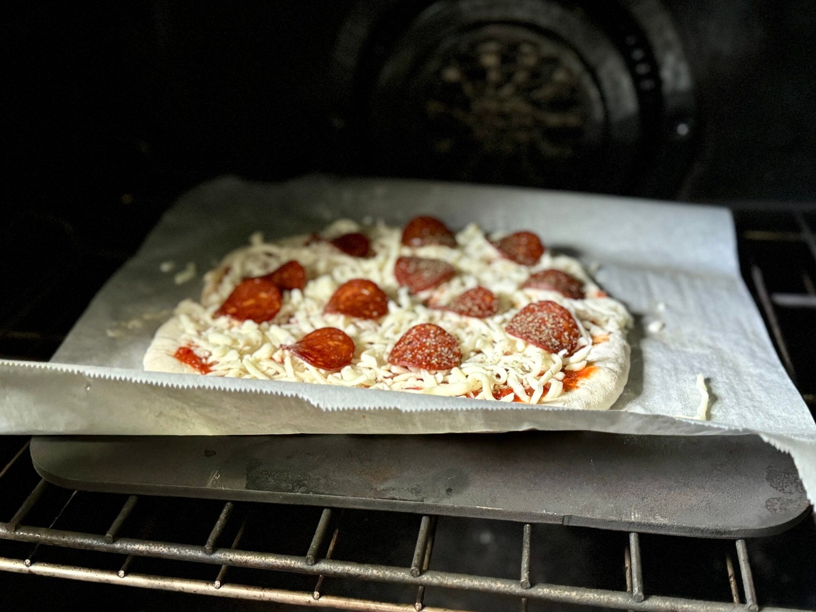 skinny pizza dough being baked on a baking steel
