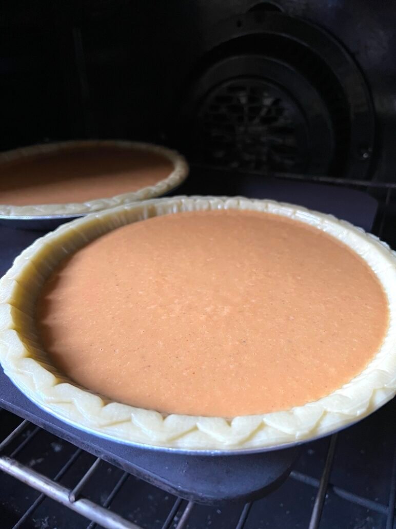 this is a photo of pumpkin pie going into the oven to cook